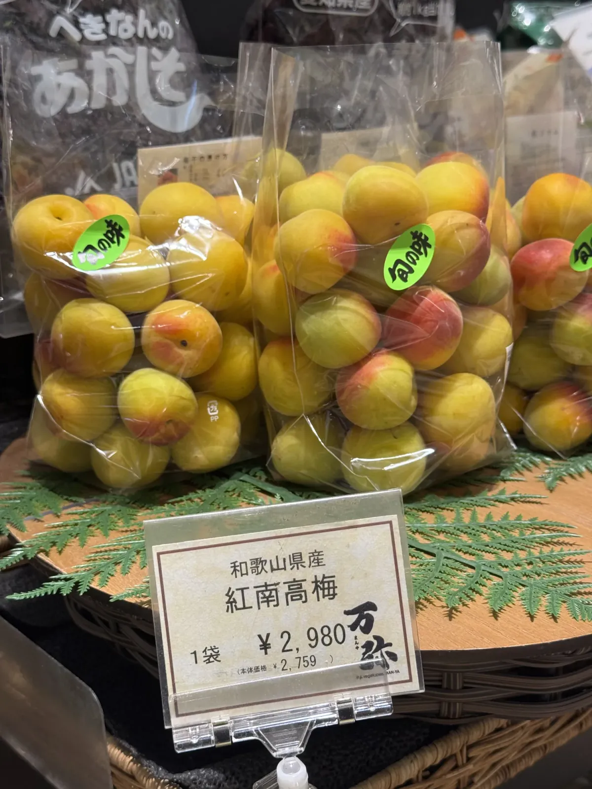 Bags of ripe Nanko ume plums on a shop display with a price card reading 2,980 yen